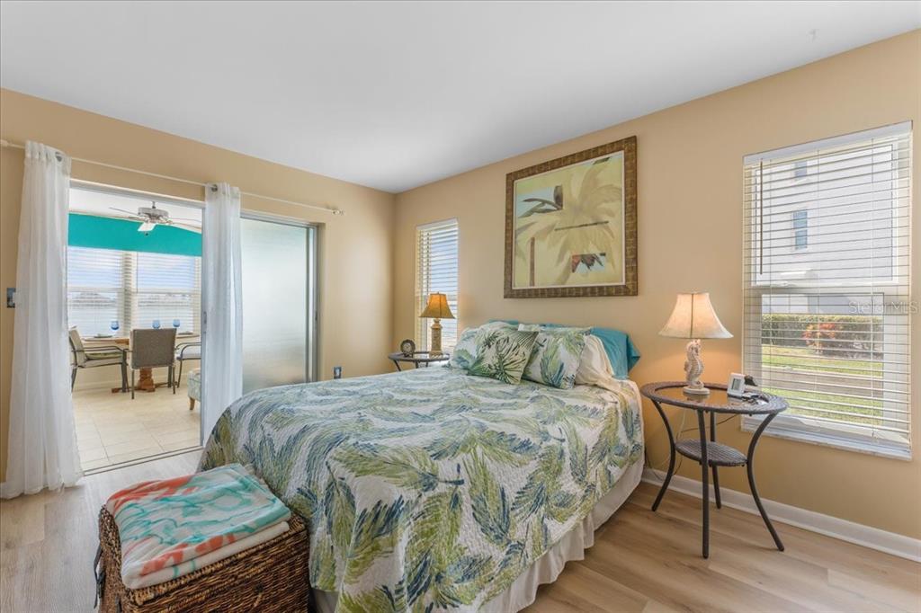A bedroom features a bed with a palm-print quilt, a side table, and a sliding door — 5020 BRITTANY DRIVE S UNIT 118, ST PETERSBURG, FL