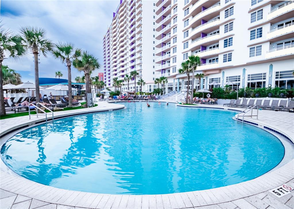 A large outdoor swimming pool is situated in front of a tall multi-story resort building — 350 N ATLANTIC AVENUE UNIT 2333, DAYTONA BEACH, FL