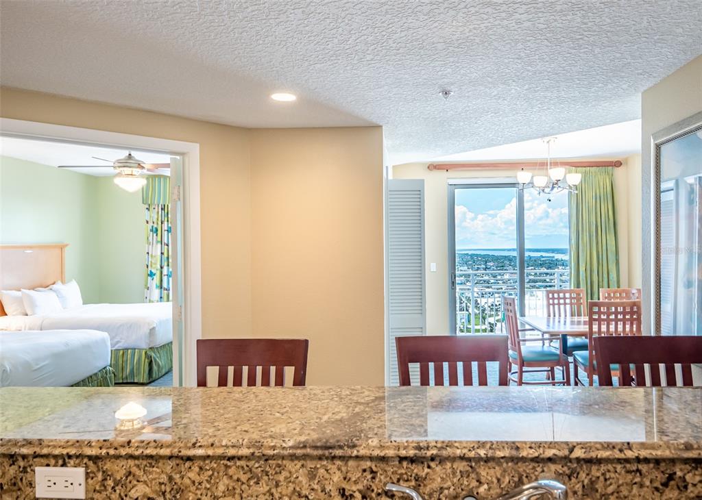 A granite kitchen counter overlooks a dining area with a balcony view and a bedroom — 350 N ATLANTIC AVENUE UNIT 2333, DAYTONA BEACH, FL