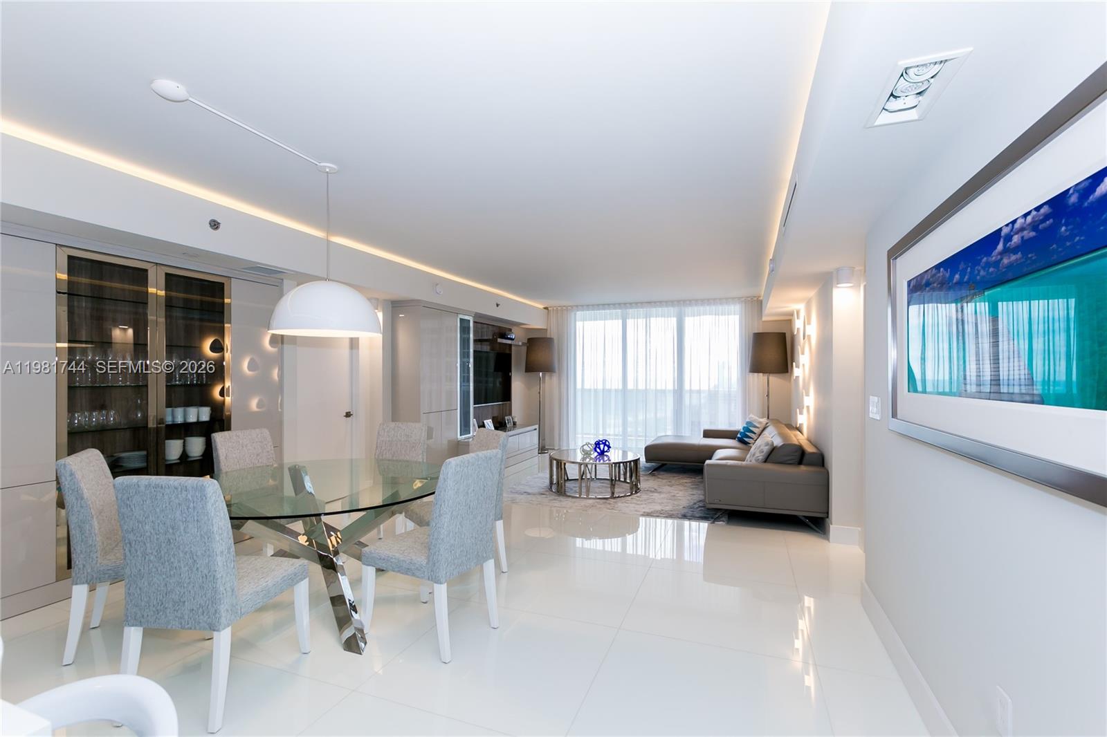 A modern open-concept living and dining area features white tile floors and neutral furnishings — 1830 S Ocean Dr # 2903, Hallandale Beach FL 33009, HALLANDALE BEACH, FL