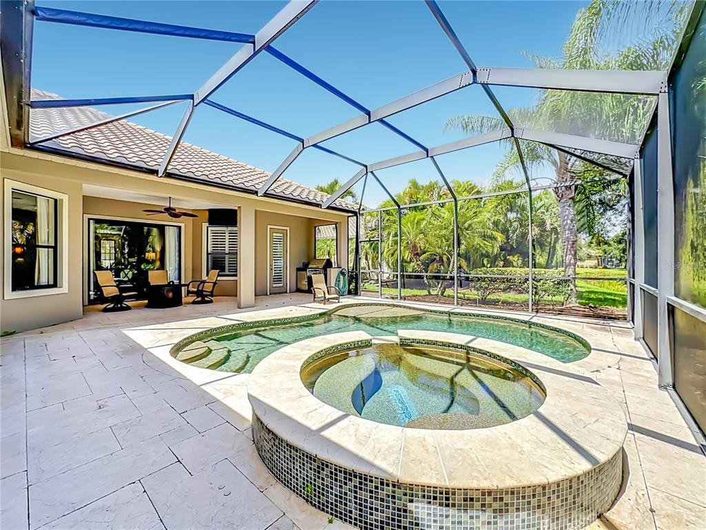 A screened-in patio features a swimming pool, a raised hot tub, and outdoor seating — 7668 SILVERWOOD COURT, LAKEWOOD RANCH, FL