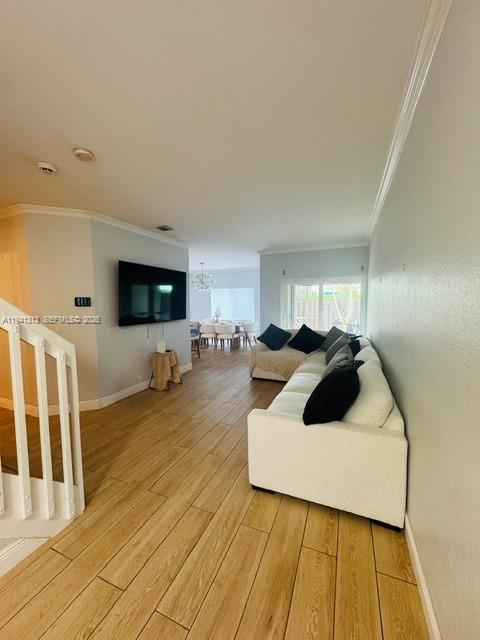 A living room features light wood-look tile flooring, a white sofa, and a wall-mounted television — 10919 NW 67th Ter, Doral FL 33178, DORAL, FL