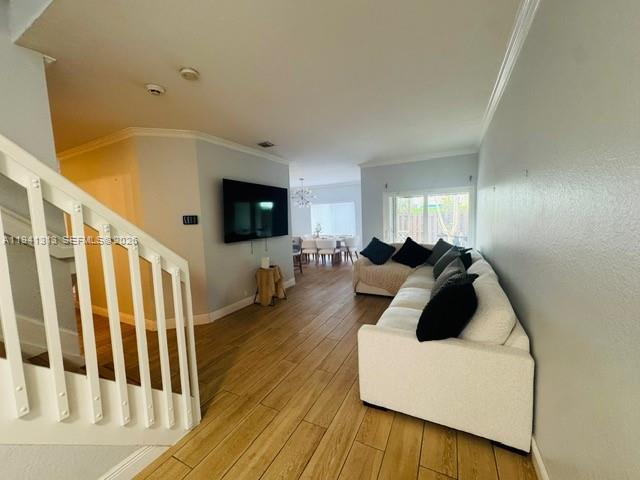 A living room features light wood-look flooring, a white sofa, and a wall-mounted television — 10919 NW 67th Ter, Doral FL 33178, DORAL, FL