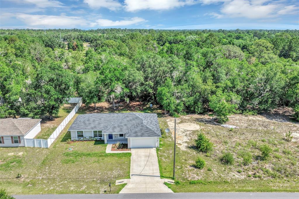 An aerial view shows a single-story house with a gray roof and a concrete driveway — 5 LOCUST RADIAL CIRCLE, OCALA, FL