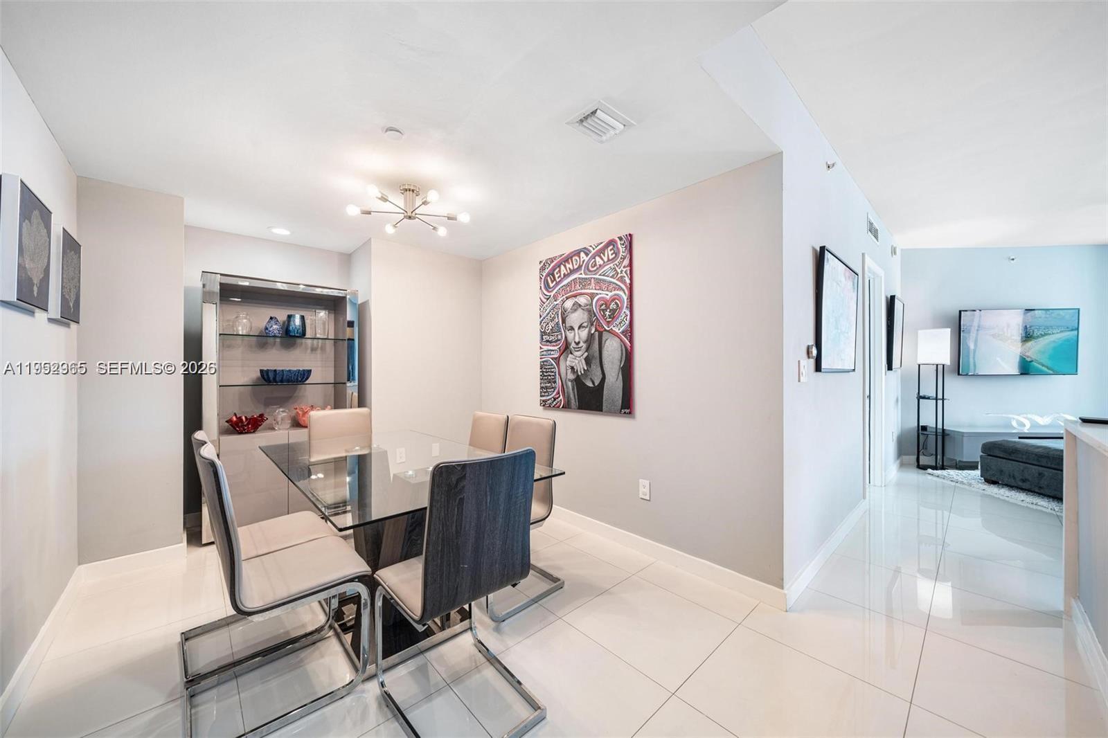 A dining area features a glass table, modern chairs, and a large pop-art portrait — 350 S Miami Ave # 2505, Miami FL 33130, MIAMI, FL