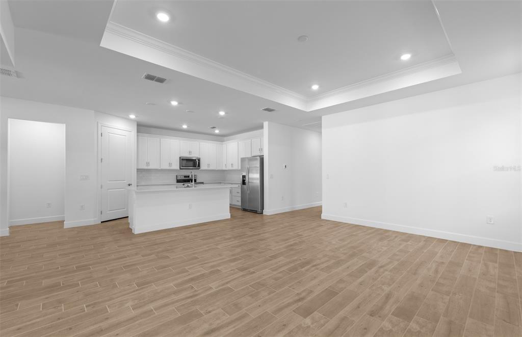 An open-concept kitchen with white cabinetry and a breakfast bar overlooks a spacious living area — 6974 MINNEOLA COURT, NOKOMIS, FL