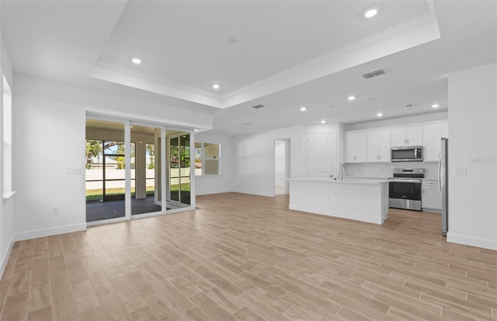 An open-concept kitchen and living area with white cabinetry, a kitchen island, and sliding doors — 6974 MINNEOLA COURT, NOKOMIS, FL
