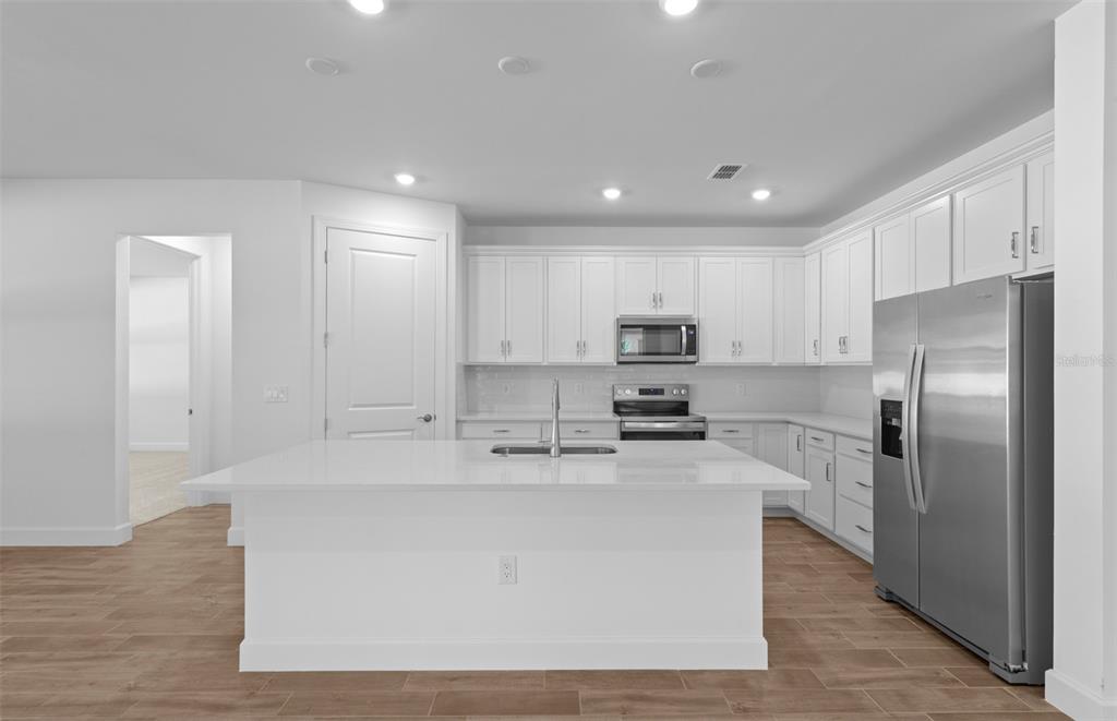 A modern kitchen features white cabinetry, stainless steel appliances, and a large central island — 6974 MINNEOLA COURT, NOKOMIS, FL