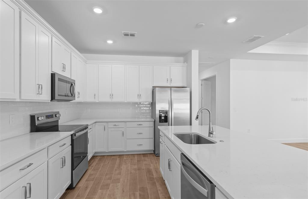 A modern kitchen features white cabinetry, stainless steel appliances, and a large central island — 6974 MINNEOLA COURT, NOKOMIS, FL