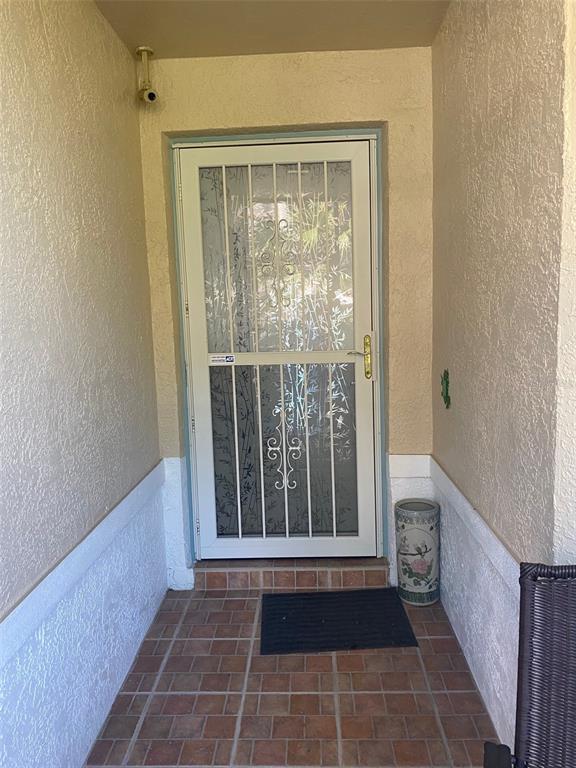 A covered entryway features a white security screen door, tiled flooring, and a decorative ceramic planter — 2602 EDGEWATER COURT, PALMETTO, FL