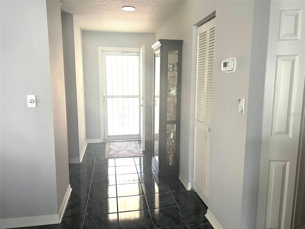 A tiled entryway features a front door with a security screen and a tall display cabinet — 2602 EDGEWATER COURT, PALMETTO, FL