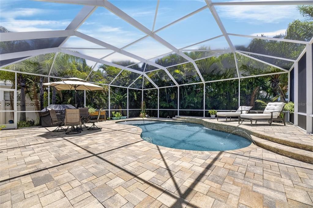A screened-in patio features a swimming pool, stone pavers, outdoor furniture, and lush landscaping — 5226 BRIGHTON SHORE DRIVE, APOLLO BEACH, FL