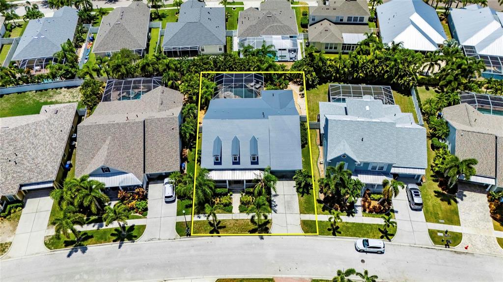 An aerial view shows a residential house with a pool enclosure and a paved driveway — 5226 BRIGHTON SHORE DRIVE, APOLLO BEACH, FL