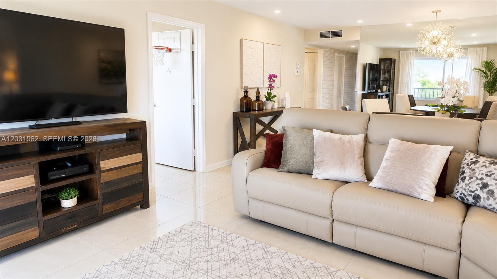 A living room features a large television, a leather sofa, and tile flooring — 4570 NW 18th Ave # 506, Deerfield Beach FL 33064, DEERFIELD BEACH, FL
