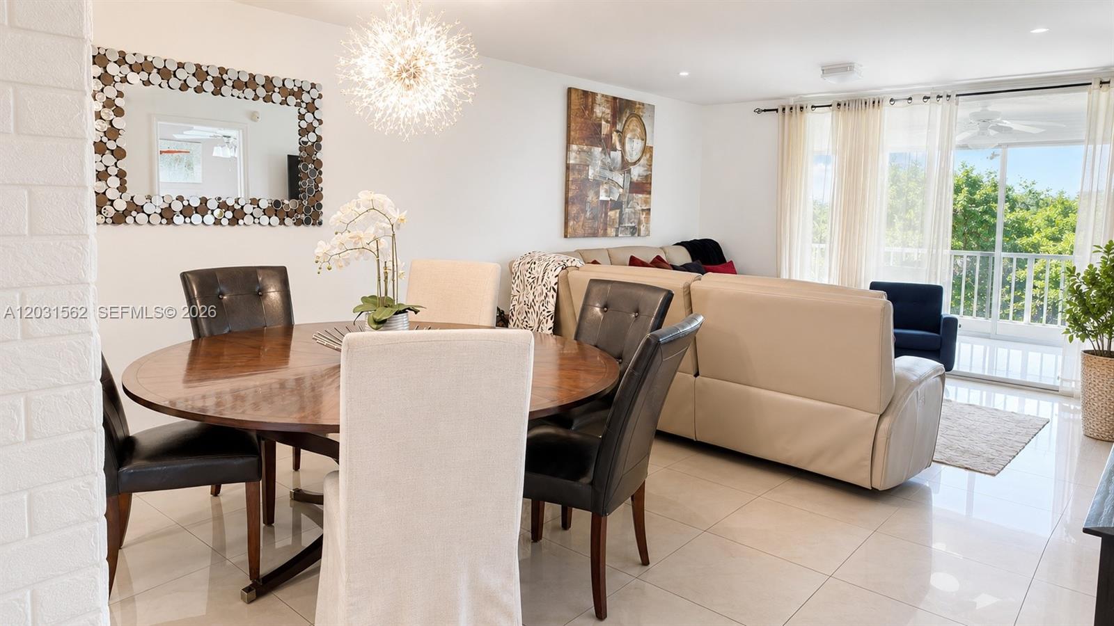 A dining area with a round wooden table sits adjacent to a living room — 4570 NW 18th Ave # 506, Deerfield Beach FL 33064, DEERFIELD BEACH, FL