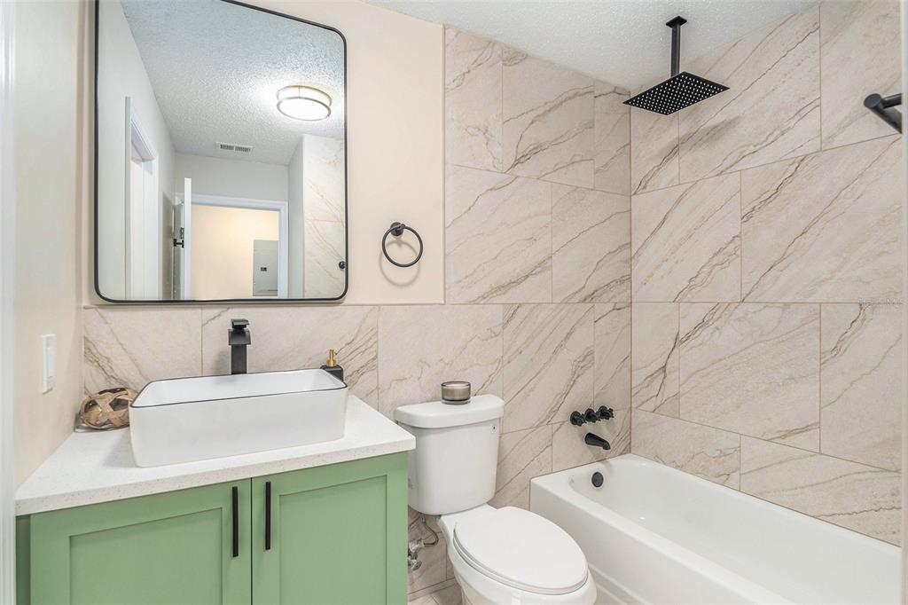 A bathroom features a green vanity, vessel sink, toilet, and a tiled tub-shower combination — 3822 CORTEZ DRIVE UNIT D, TAMPA, FL