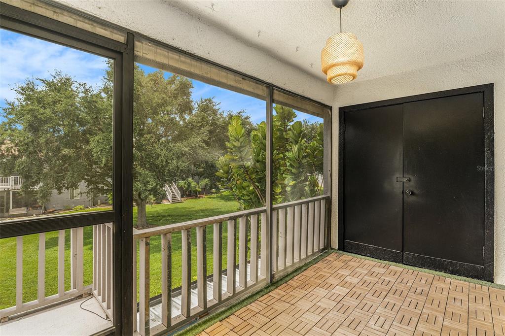 A screened-in balcony features tiled flooring, a hanging light fixture, and a black storage closet — 3822 CORTEZ DRIVE UNIT D, TAMPA, FL