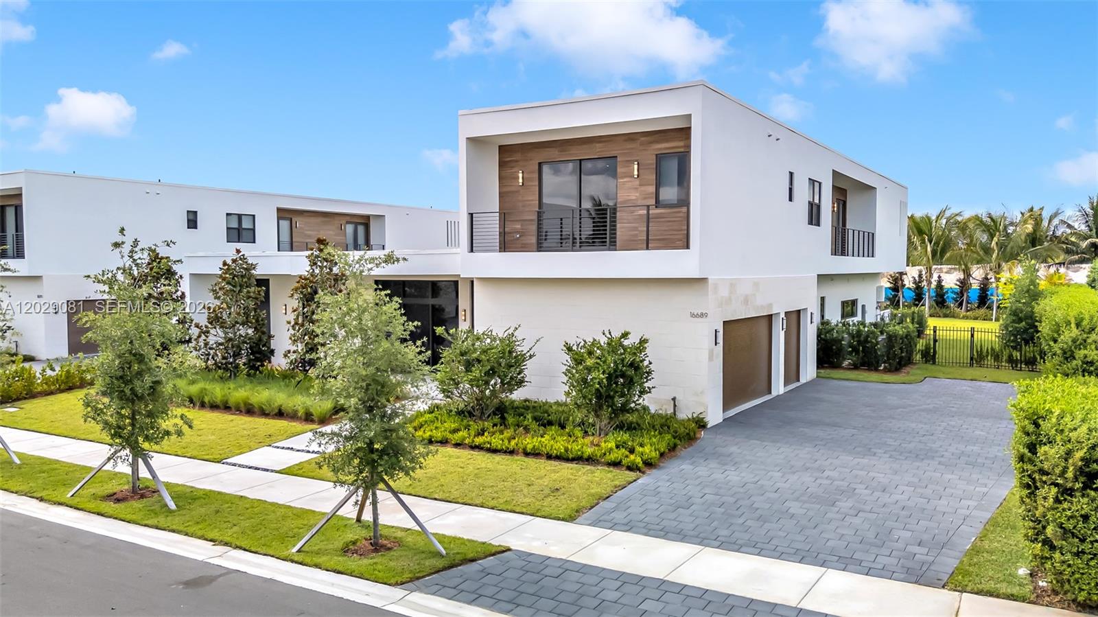 A modern two-story house features white stucco walls, wood-paneled accents, and a paved driveway — 16689 N Botaniko Dr N, Weston FL 33326, WESTON, FL