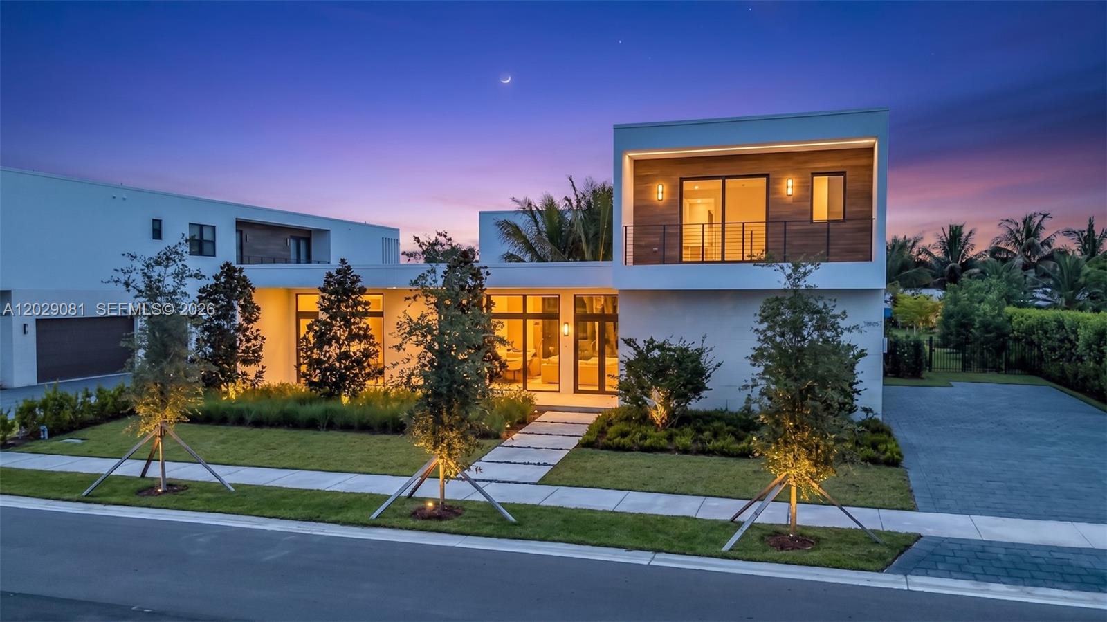 A modern two-story house with a flat roof, wood accents, and a paved driveway at dusk — 16689 N Botaniko Dr N, Weston FL 33326, WESTON, FL