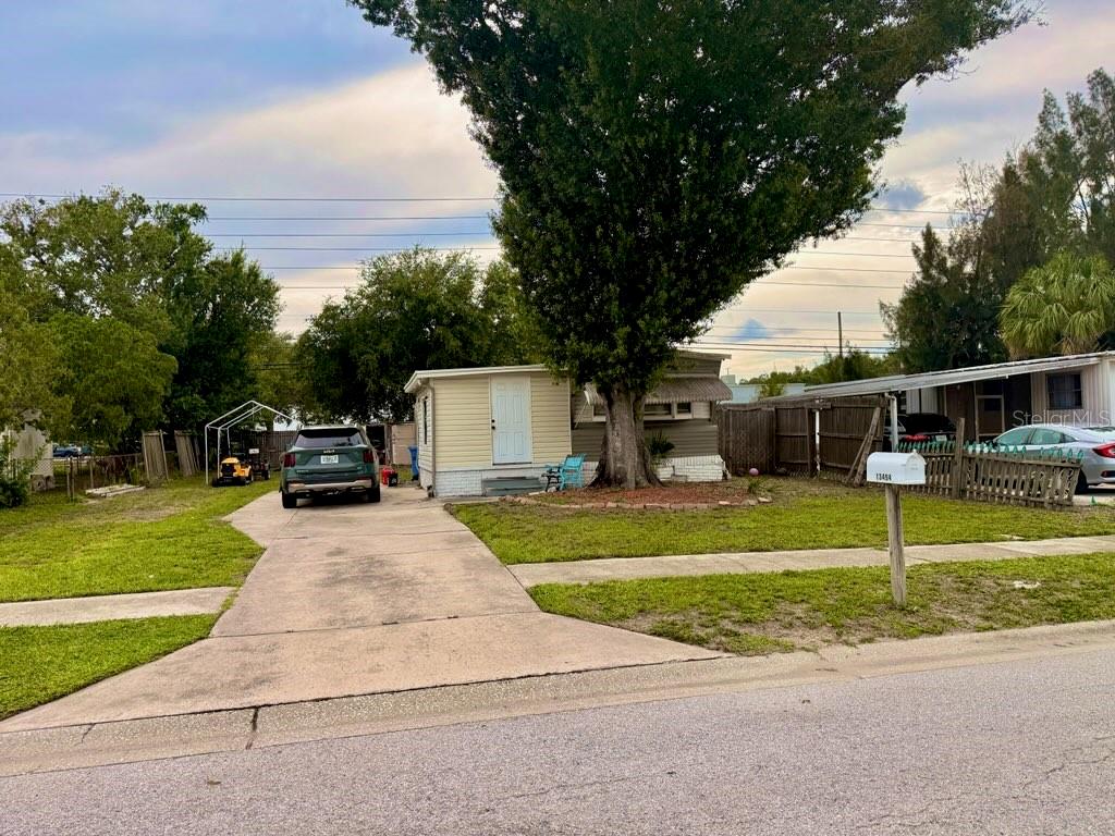 A single-story house with a driveway, a large tree, and a mailbox in the front yard — 13494 61ST WAY N, CLEARWATER, FL