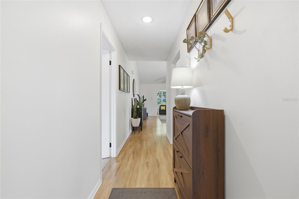 A hallway with light wood flooring, a wooden shoe cabinet, and wall-mounted coat hooks — 250 HOMEWOOD AVENUE UNIT 11A, DEBARY, FL