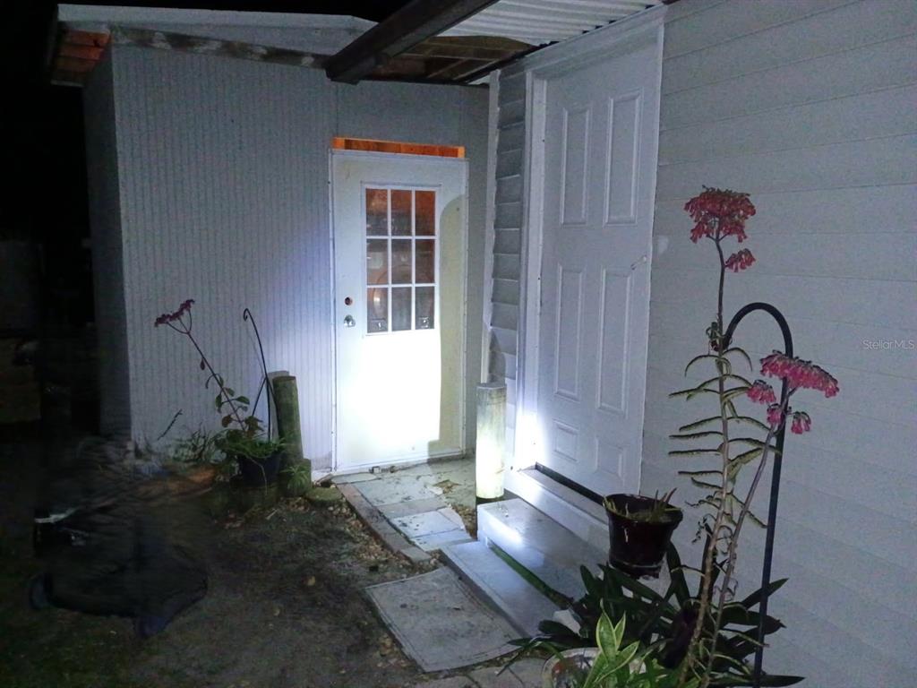 An exterior view of a house at night showing two white doors and potted plants — 15373 ORCHID DRIVE, PUNTA GORDA, FL