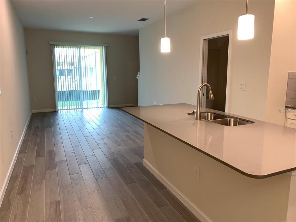A kitchen island with a sink overlooks an open living area with sliding glass doors — 9831 RED EAGLE DRIVE, ORLANDO, FL