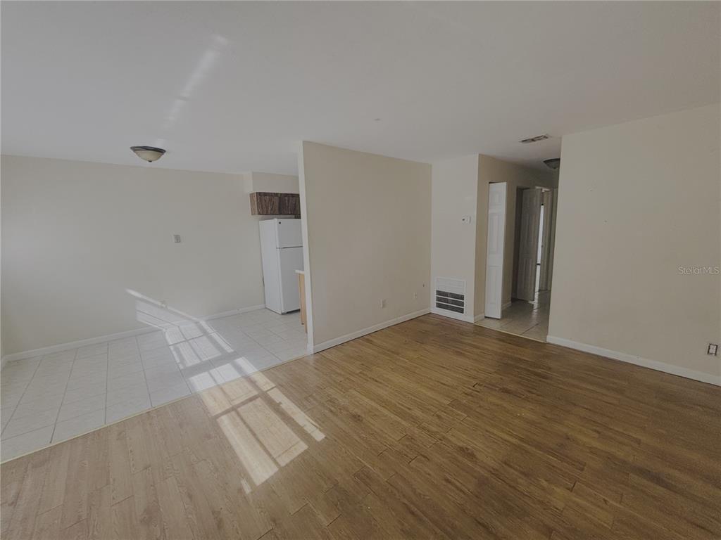 An open-concept living area features wood-look flooring, a tiled kitchen space, and a white refrigerator — 1915 SW 70 TERRACE UNIT B, GAINESVILLE, FL
