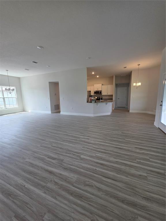 An open-concept living area features light wood-look flooring and a kitchen with white cabinetry — 461 SW BELLFLOWER DRIVE, LAKE CITY, FL