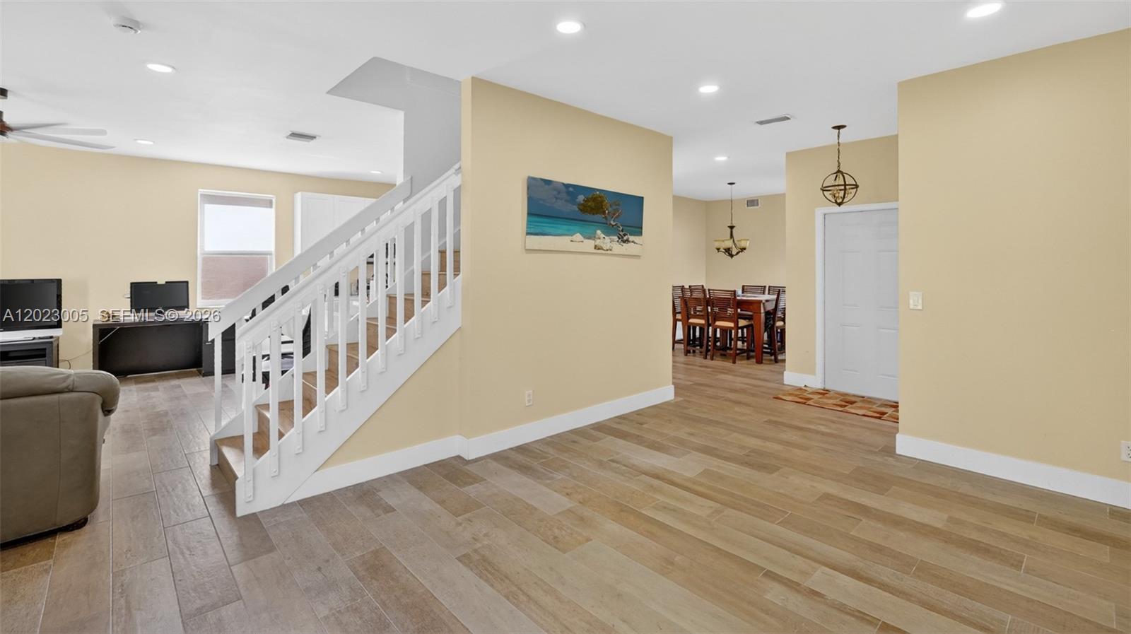 A living area with light wood-look tile floors, a white staircase, and a dining room — 17731 SW 23rd St, Miramar FL 33029, MIRAMAR, FL