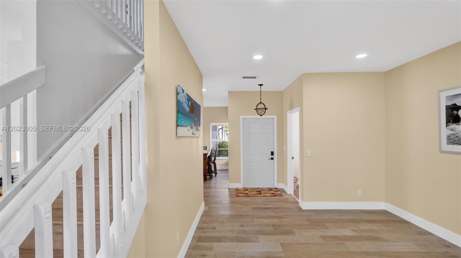 An entryway features wood-look tile flooring, a white staircase, and a front door — 17731 SW 23rd St, Miramar FL 33029, MIRAMAR, FL