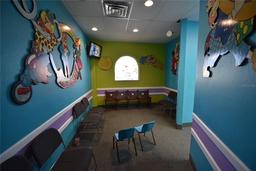 A colorful waiting room features clown-themed wall art, multiple chairs, and a small arched window — 5124 US HIGHWAY 19 UNIT 5120, NEW PORT RICHEY, FL