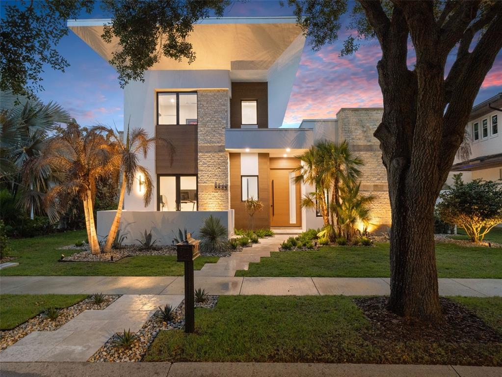 A modern entryway features a large wooden pivot door opening to an outdoor patio area — 8643 FARTHINGTON WAY, ORLANDO, FL
