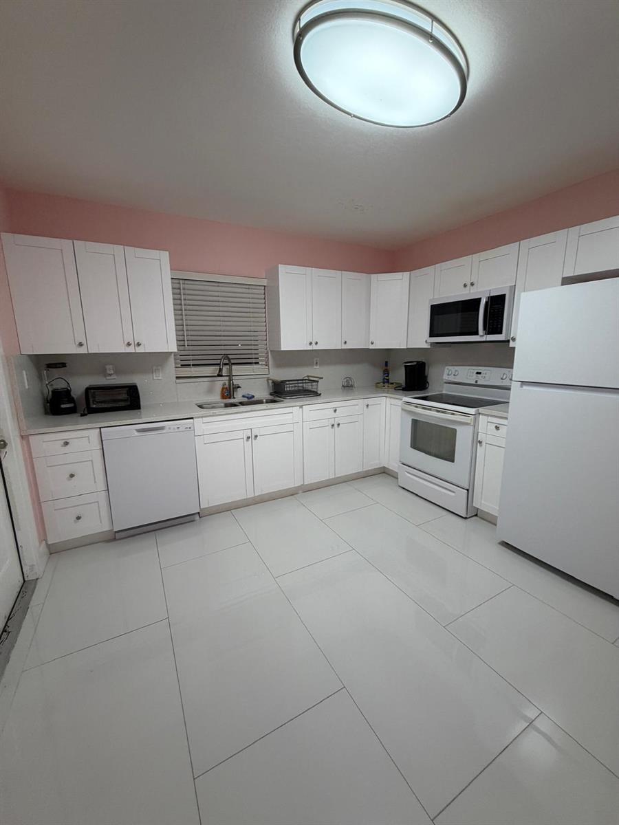 A kitchen features white cabinets, white appliances, a light countertop, and light-colored tile flooring — 1700 NE 146th Street, Miami FL 33181, MIAMI, FL