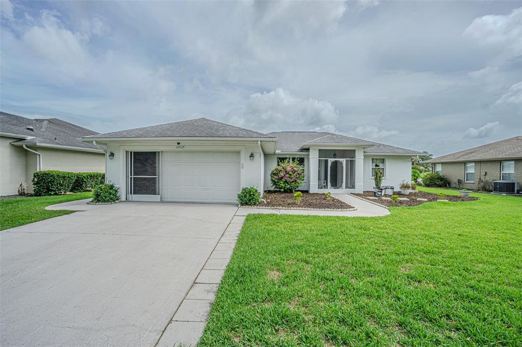 A single-story house with a white garage, a concrete driveway, and a landscaped front yard — 10535 MOSHIE LANE, SAN ANTONIO, FL
