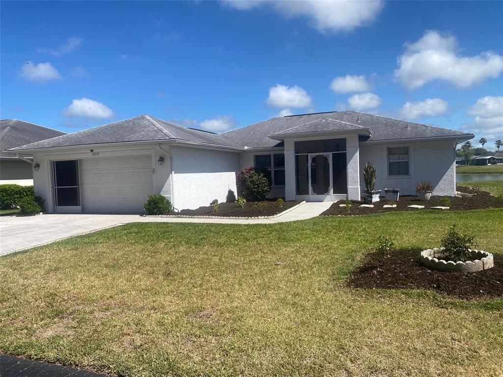A single-story house with a white stucco exterior, a two-car garage, and a front entryway — 10535 MOSHIE LANE, SAN ANTONIO, FL