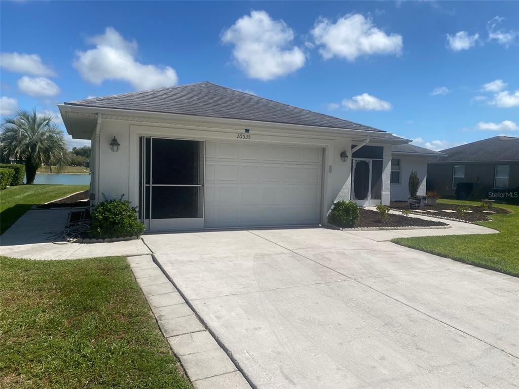 A white single-story house features a two-car garage, a screen door, and a concrete driveway — 10535 MOSHIE LANE, SAN ANTONIO, FL