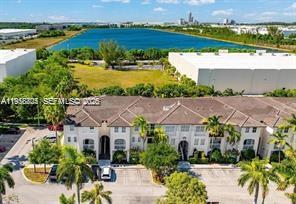 An aerial view shows a multi-story residential building with a parking lot and nearby lake — 11603 NW 89th St # 215, Doral FL 33178, DORAL, FL