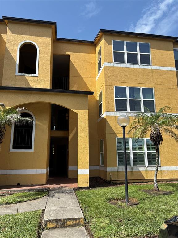A three-story yellow apartment building features arched windows and a central covered entryway — 4642 COMMANDER DRIVE UNIT 938, ORLANDO, FL