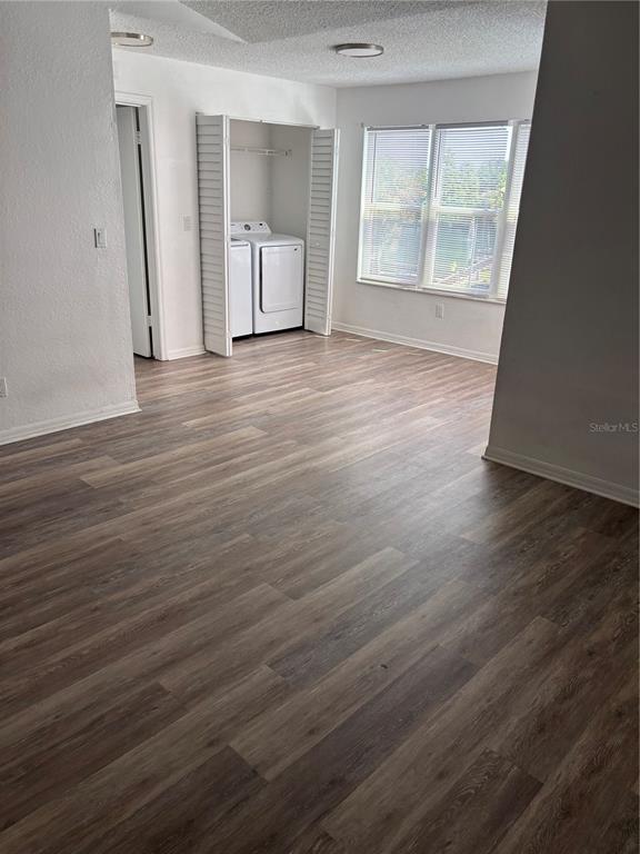 A room with wood-look flooring and a laundry closet containing a washer and dryer — 4642 COMMANDER DRIVE UNIT 938, ORLANDO, FL