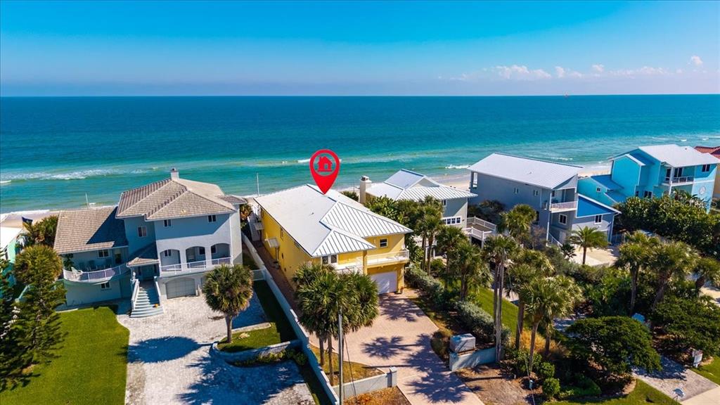 An aerial view of a yellow beachfront house with a metal roof and palm trees — 5609 S ATLANTIC AVENUE, NEW SMYRNA BEACH, FL
