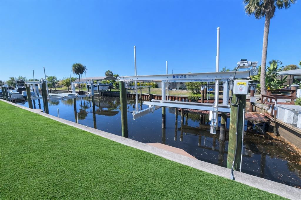 A boat lift sits over a canal next to a grassy lawn and seawall — 3211 RIVERSIDE DRIVE, PUNTA GORDA, FL