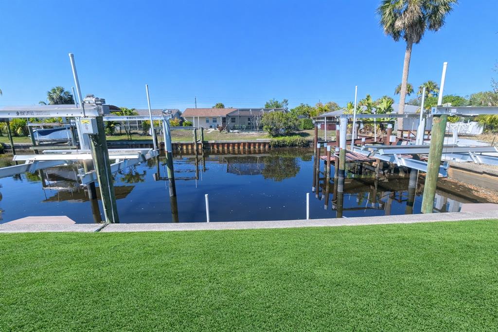 A view of a canal with two boat lifts and artificial turf in the foreground — 3211 RIVERSIDE DRIVE, PUNTA GORDA, FL