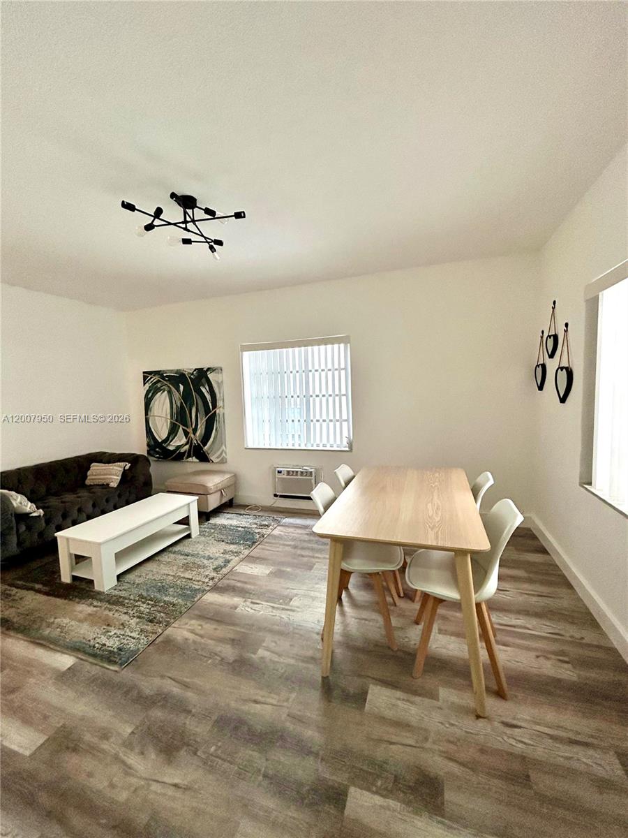 This living and dining area features wood-look flooring, a modern light fixture, and white walls — 215 30th St # 17, Miami Beach FL 33140, MIAMI BEACH, FL