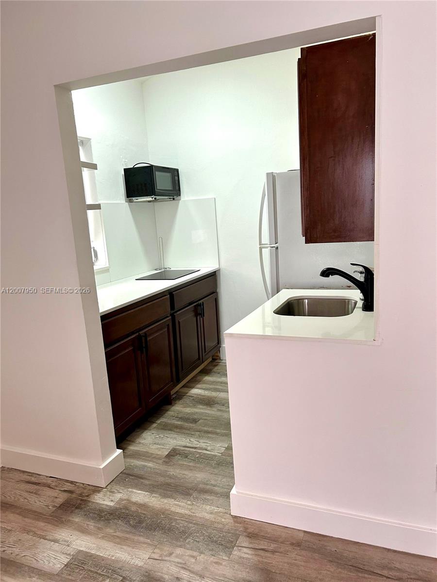 A small kitchen features dark wood cabinets, white countertops, and stainless steel appliances — 215 30th St # 17, Miami Beach FL 33140, MIAMI BEACH, FL