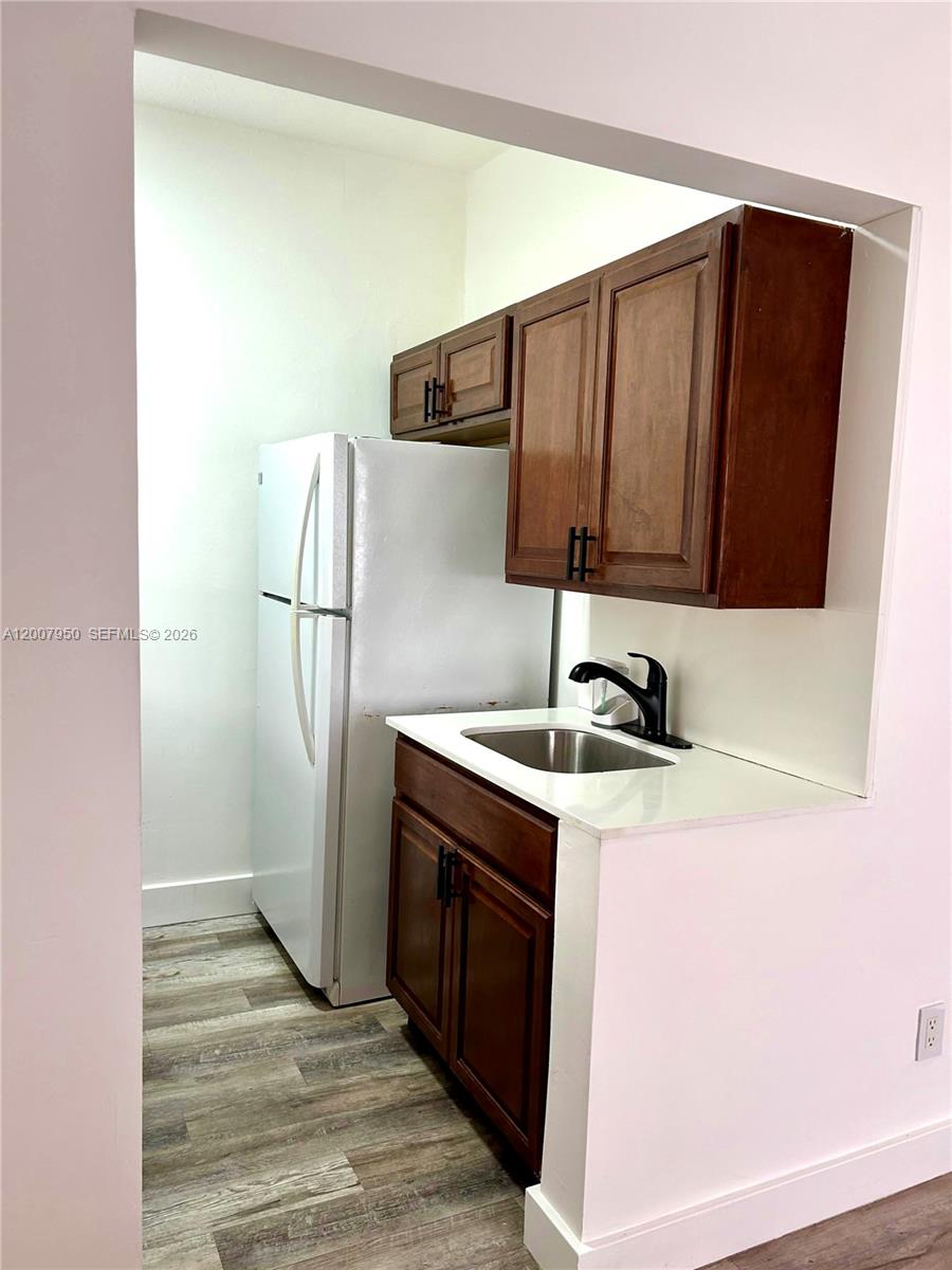 A small kitchenette features wood cabinets, a white countertop, a sink, and a refrigerator — 215 30th St # 17, Miami Beach FL 33140, MIAMI BEACH, FL