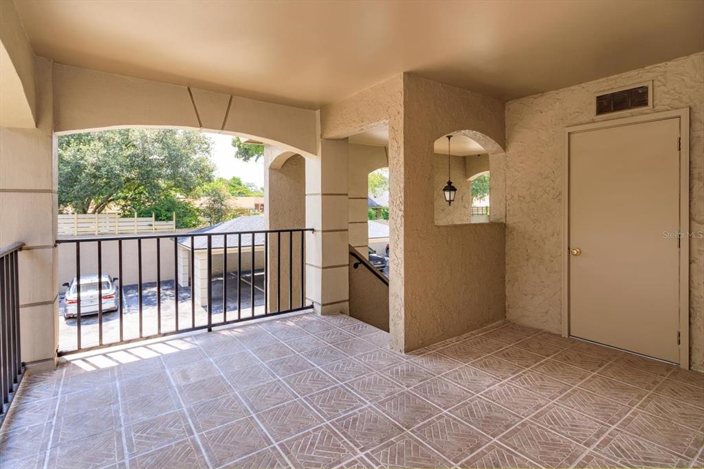 A covered balcony features tiled flooring, a metal railing, and a beige door — 1055 KENSINGTON PARK DRIVE UNIT 711, ALTAMONTE SPRINGS, FL