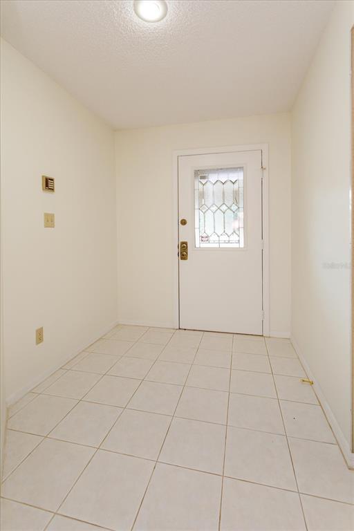 An entryway with white tile flooring, plain walls, and a white door with glass panels — 1055 KENSINGTON PARK DRIVE UNIT 711, ALTAMONTE SPRINGS, FL