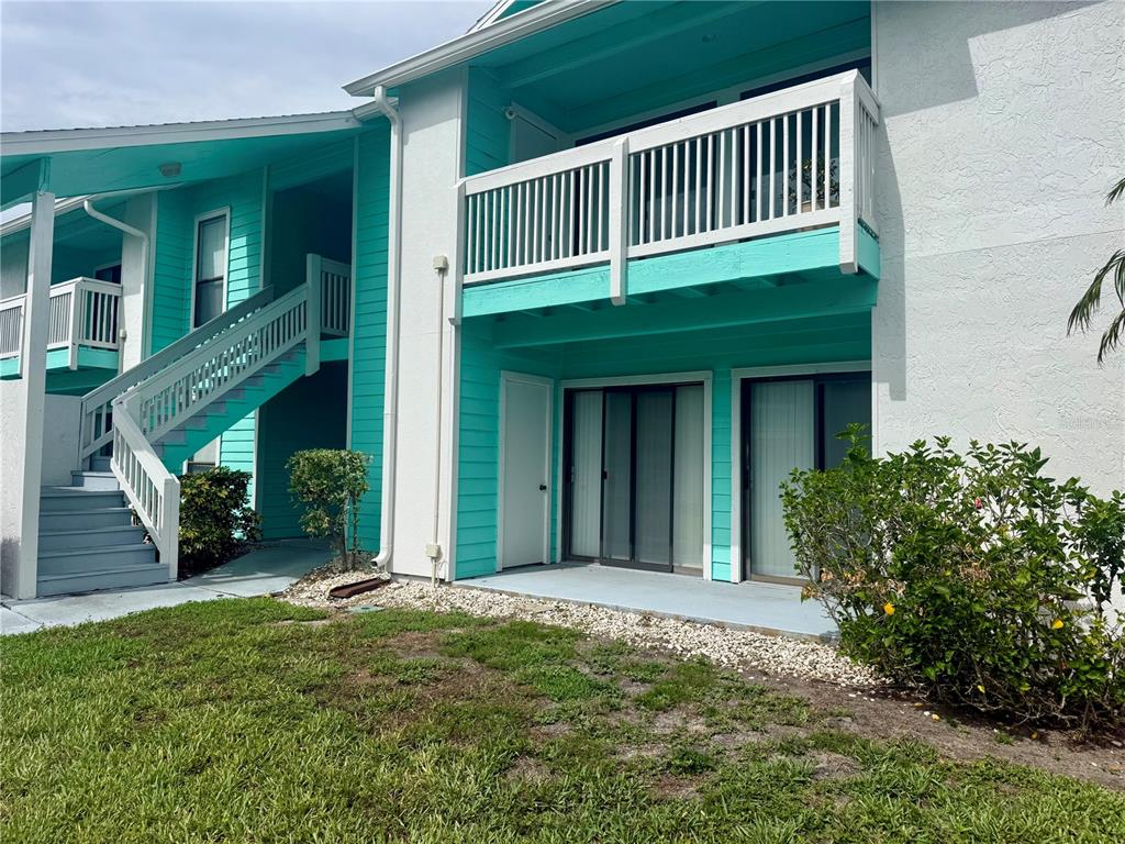 A two-story apartment building features turquoise siding, a white balcony, and an exterior staircase — 455 ALT 19 S UNIT 47, PALM HARBOR, FL