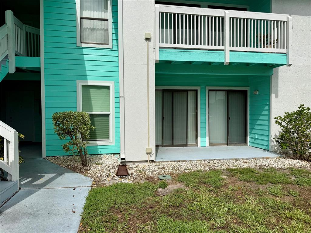 The exterior of a two-story apartment building features teal siding, a balcony, and sliding doors — 455 ALT 19 S UNIT 47, PALM HARBOR, FL